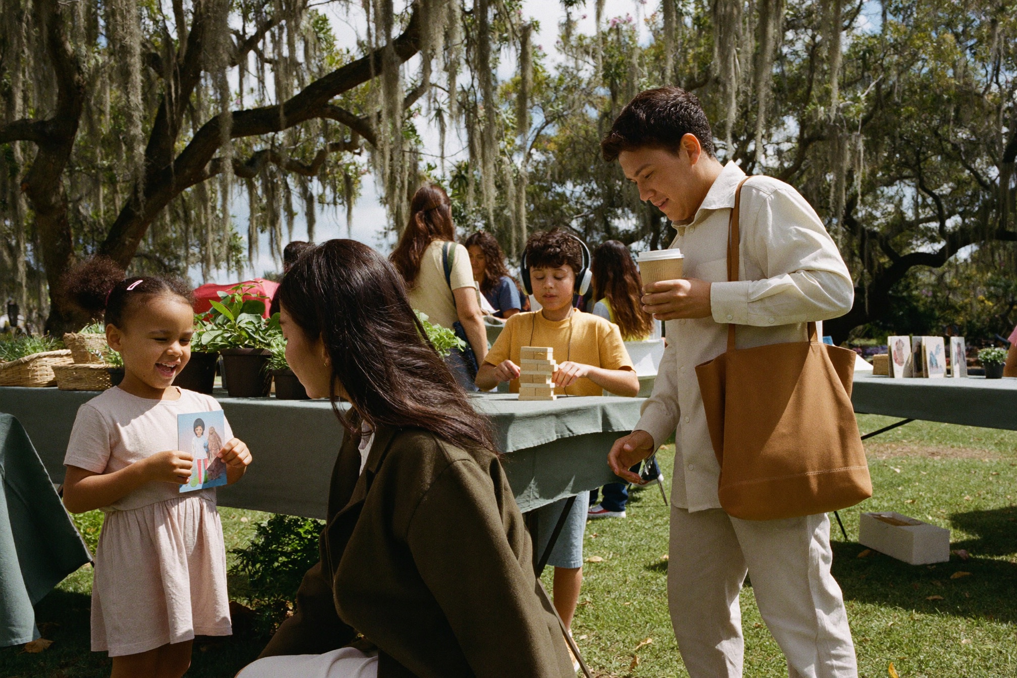 Families and local providers meeting at an outdoor community fair under oak trees